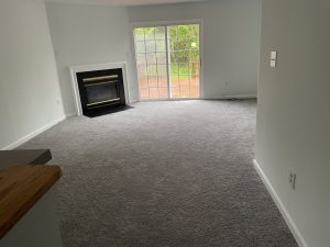 Interior room with freshly painted walls and carpet, ready for flooring installation.